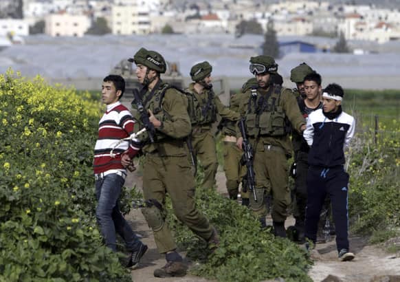 Israeli soldiers arrest Palestinian youths during a protest north of the West Bank city of Jenin in support to the Palestinian prisoners.