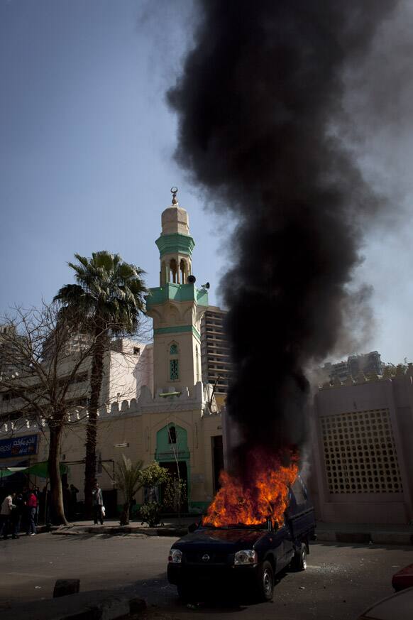 A police pickup truck burns after being set on fire by Egyptian Ultras, hard-core soccer fans, during an anti government rally in front of the Giza security directorate, background, in Giza, Egypt.