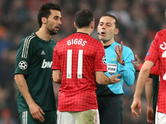 Manchester United`s Ryan Giggs argues with referee Cuneyt Cakir after he gave a yellow card to teammate Nani during their Champions League round of 16 soccer match at Old Trafford Stadium, Manchester, England.