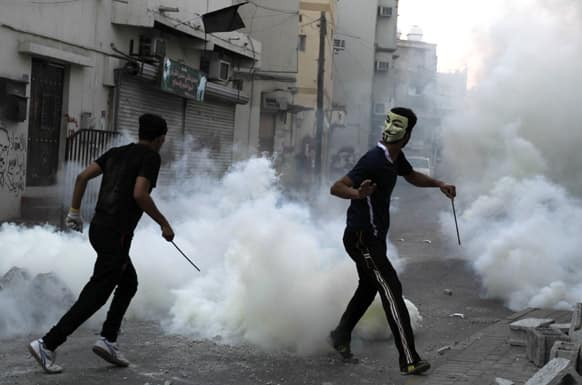 Bahraini anti-government protesters carry steel rods into clashes with riot police firing tear gas and birdshot in Manama, Bahrain.