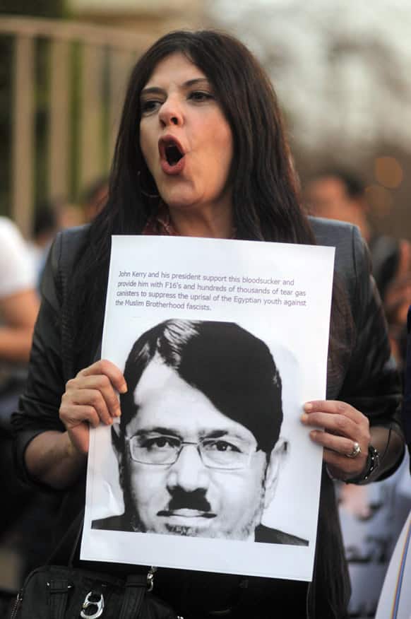 An Egyptian activist shouts slogans as she holds a poster depicting Egyptian Islamist President Mohammed Morsi doctored to resemble Adolf Hitler during a protest outside the Egyptian foreign ministry during a visit by US Secretary of State John Kerry in Cairo.