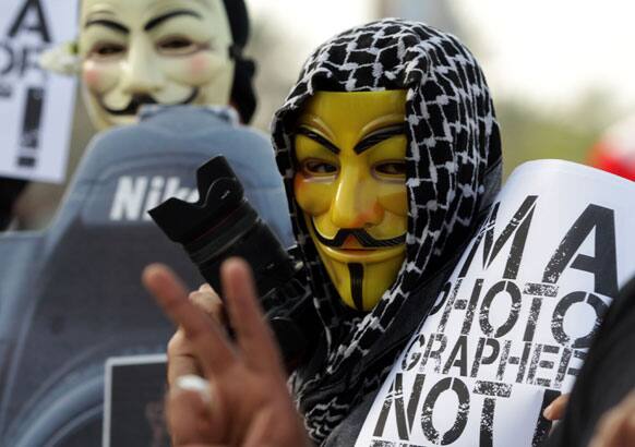 A Bahraini anti-government protester carries a camera and sign reading