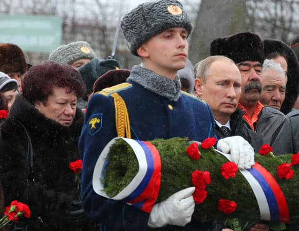 Russian President Vladimir Putin, third right, with relatives of Russian paratroopers who were killed in 2000 during the war in Chechnya, lays flowers at the monument to soldiers of the Pskov Airborne Division in Pskov, about 600 kms (375 miles) northwest of Moscow.