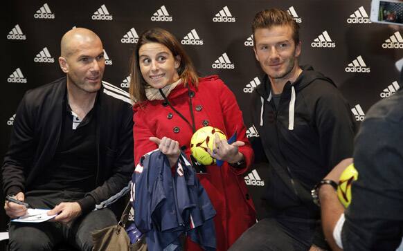 Soccer legend Zinedine Zidane, left, and Paris Saint Germain`s David Beckham pose for a photograph with unidentified fan as they sign autographs, during a media event, in a sports store, on the Champs Elysees Avenue, in Paris.