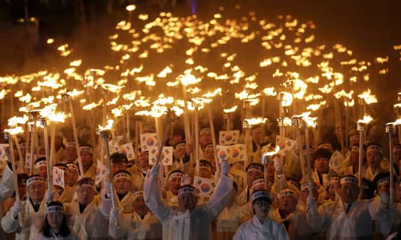 South Koreans wearing traditional Korean costumes carry torches and national flags as they march on the street during a ceremony to celebrate the March First Independence Movement Day, the anniversary of the 1919 uprising against Japanese colonial rule, in Cheonan, south of Seoul.