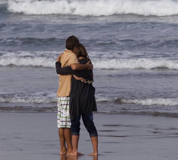 Meg Strange, wife of Adam Strange is comforted by friend Simon Shephard, as people gather on Muriwai Beach near Auckland, New Zealand.