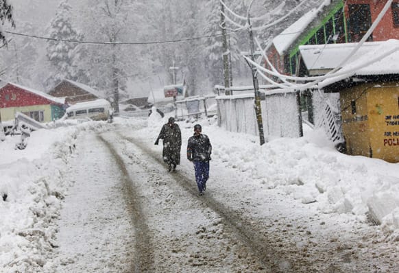 Kashmiris walk through a snow-covered road as it snows at Tangmarg, about 38 kilometers (24 miles) northwest of Srinagar.