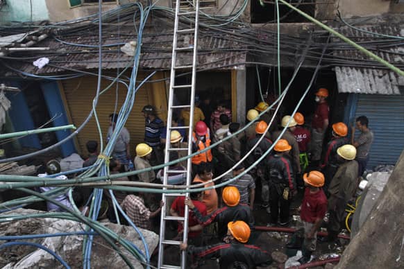 Firemen and rescuers wait outside an illegal six-story plastics market where a fire broke out early in the morning in Kolkata.