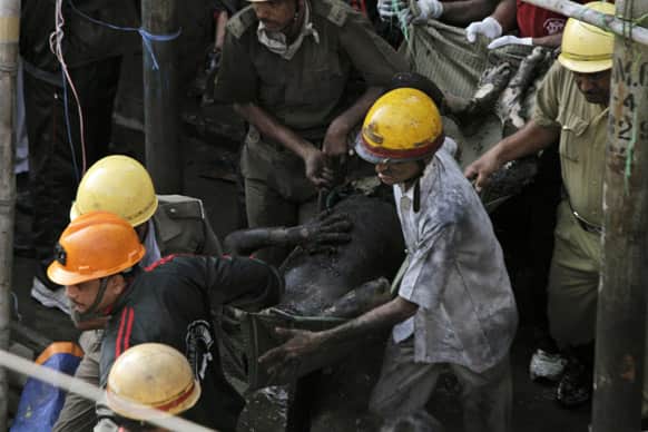Rescuers carry a victim`s charred body after a fire broke out early in the morning at an illegal six-story plastics market in Kolkata.