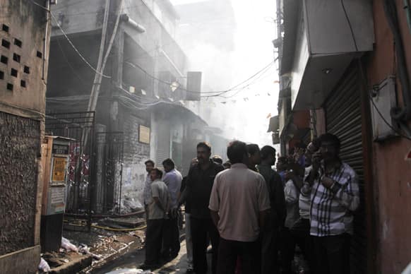 Residents and onlookers wait outside smoldering buildings where a fire broke out at an illegal six-story plastics market in Kolkata.