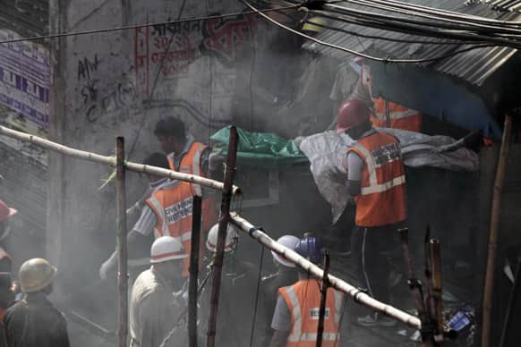 Rescue workers carry a victim`s body wrapped in plastic bag after a fire broke out early morning at an illegal six-story plastics market in Kolkata.