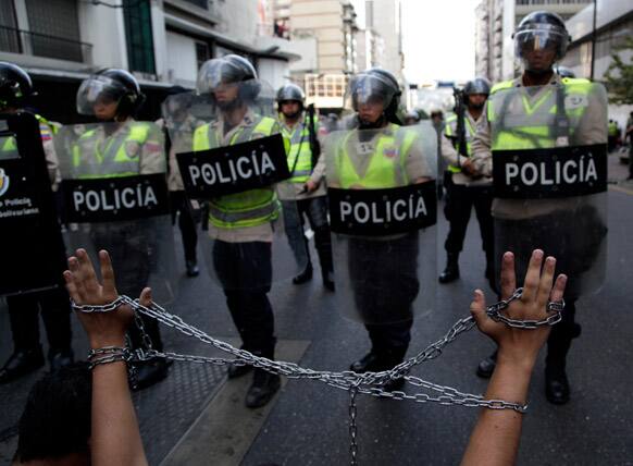 A student raises his arms tied with a chain during a protest demanding information about the health of Venezuela`s President Hugo Chavez in Caracas, Venezuela.