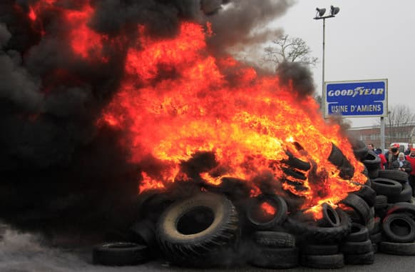 Goodyear employees gather around burning tires, outside the Goodyear tire company, in Amiens, northern France.