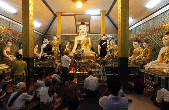Followers pray in front of Buddha statues at the Kyaik Kauk pagoda in Thanlyin, on the outskirts of Yangon, Myanmar.