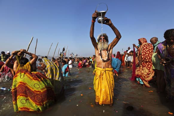 A devotee prays to the Sun God as others take holy dips at Sangam, the confluence of the Rivers Ganges, Yamuna and mythical Saraswati on Maghi Purnima, or the full-moon day, considered an auspicious bathing day, during the Maha Kumbh festival in Allahabad.