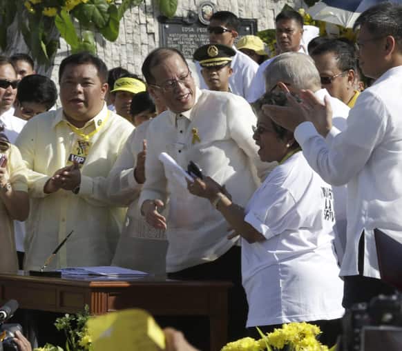 Philippine President Benigno Aquino III, center, is applauded by lawmakers after signing into law the Human Rights Victims Reparation and Recognition Act of 2013, during the 27th anniversary celebration of the People Power revolution along EDSA boulevard in Quezon city, Manila.