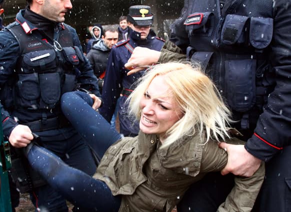 Police take away a woman protesting where former Italian Premier Silvio Berlusconi was voting, in Milan.