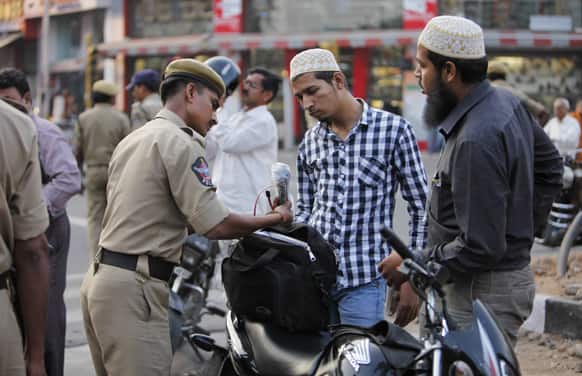 A police officer checks the bags of motorists at a street after security was enhanced following Thursday’s dual bomb attacks in Hyderabad.