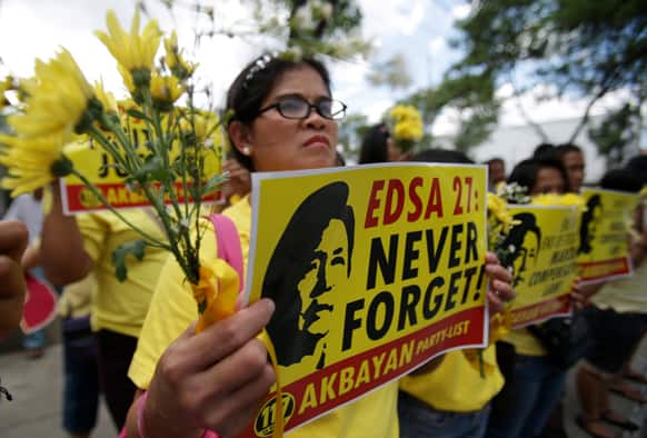 A Filipino activist displays flowers and slogans bearing an image of late Philippine strongman Ferdinand Marcos on the eve of the 27th anniversary of