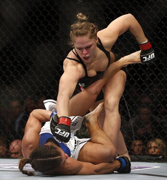Ronda Rousey, top, punches Liz Carmouche during their UFC 157 women`s bantamweight championship mixed martial arts match in Anaheim, Calif.
