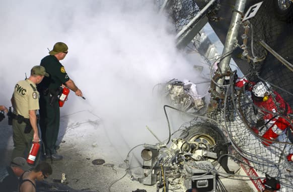 Emergency officials put out a fire from driver Kyle Larson`s engine after his car hit the wall and safety fence along the front grandstands on the final lap of a NASCAR Nationwide Series auto race at Daytona International Speedway in Daytona Beach, Fla.