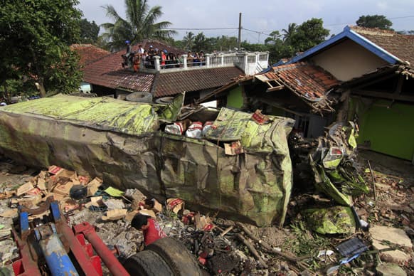 Residents examine the wreckage of a container truck that hit several houses in Cianjur, West Java, Indonesia. Police said the truck driver appeared to have lost control when his brakes failed, and hit a number of cars before slamming into several houses.