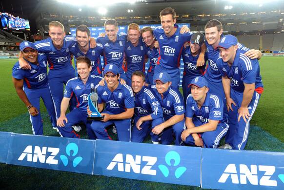 England captain Alastair Cook poses with the trophy and teammates for photographers after defeating New Zealand in their third one day international cricket match at Eden Park in Auckland, New Zealand.