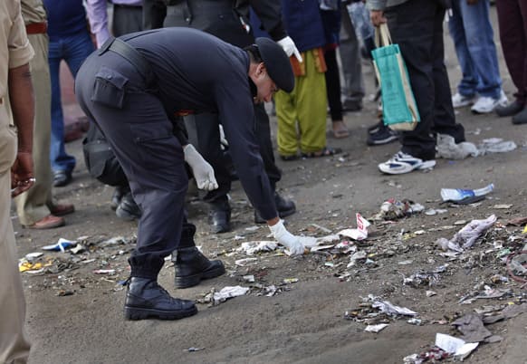 An Indian investigator looks for evidence in the debris at one of the two bomb blast sites in Hyderabad.