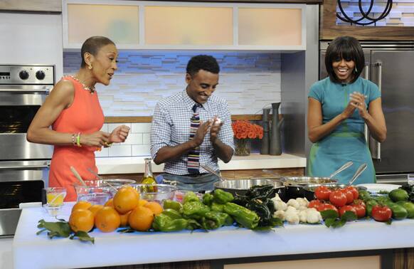 This photo released by ABC shows host Robin Roberts, chef Marcus Samuelson and first lady Michelle Obama during a taped segment on
