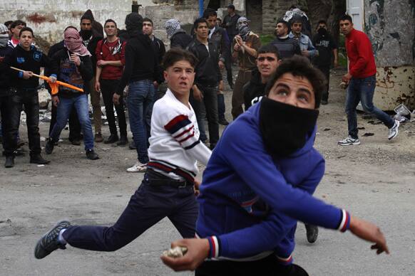 Palestinians throw stones towards Israeli soldiers, unseen, during clashes that broke out after a rally in the West Bank city of Hebron to show solidarity with prisoners on hunger strike in Israeli jails.
