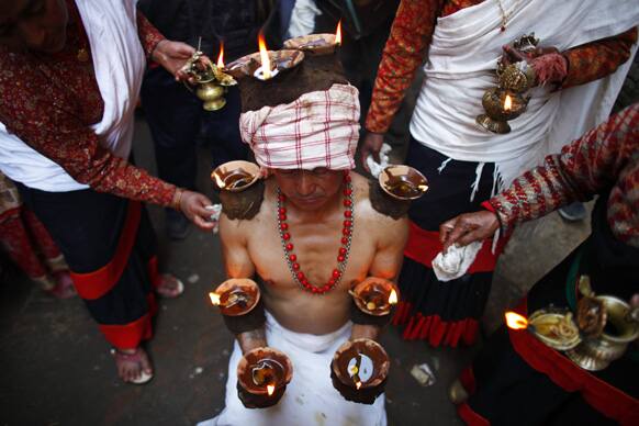 A Nepalese Hindu devotee balances lit lamps along his arms during the Madhav Narayan Festival in Lalitpur, on the outskirts of Katmandu, Nepal.