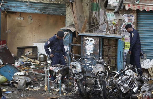 Officials of India`s National Investigation Agency look for evidence in the debris at one of the two bomb blast sites, in Hyderabad.