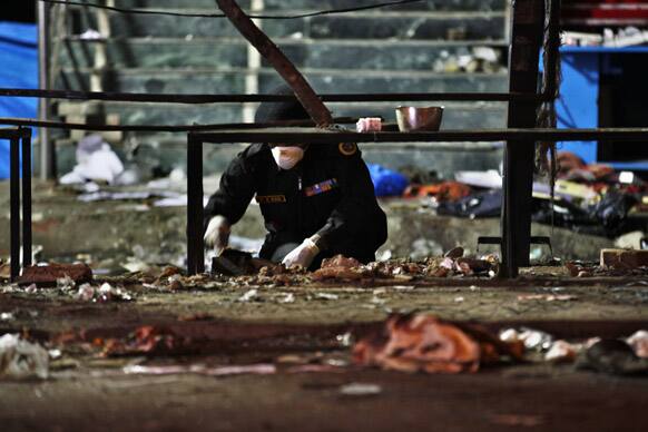 An official of India`s National Investigation Agency collects evidence from the debris at one of the two bomb blast sites, in Hyderabad.
