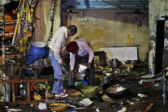 Investigative officials collect evidence from the debris at one of the two bomb blast sites, in Hyderabad.