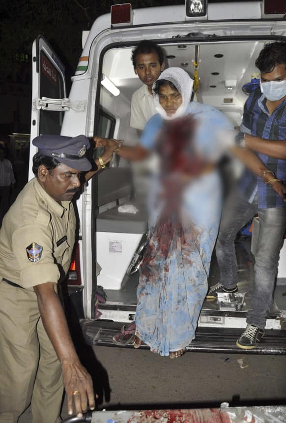An injured woman, is assisted to get down from an ambulance as she brought to a hospital after a bomb blast in Hyderabad.