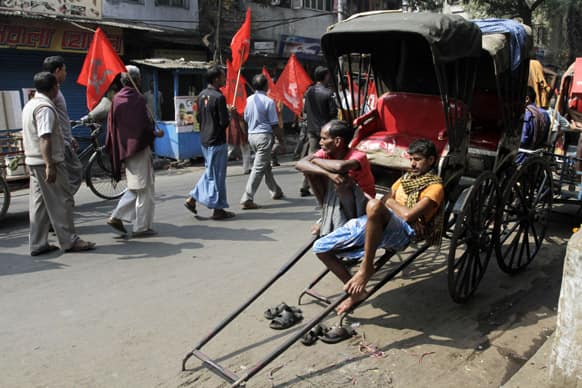 Rickshaw pullers watch members and supporters of the Communist Party of India-Marxist walk with party flags in a rally during the first day of a two-day nationwide strike called by trade unions, in Kolkata.