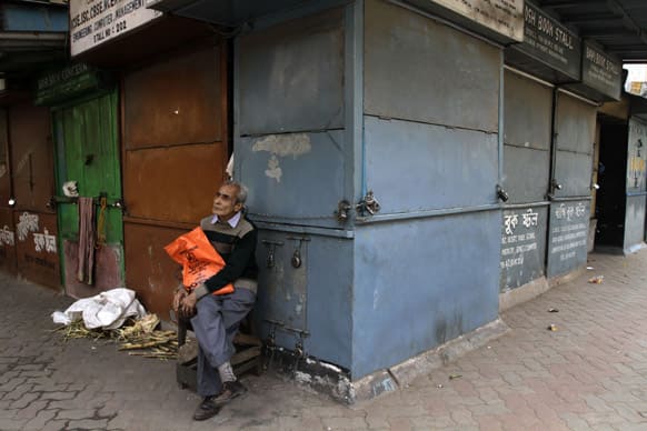 An elderly man waits for transport as he sits in front of a closed shop on the first day of a two-day nationwide strike called by trade unions in Kolkata.