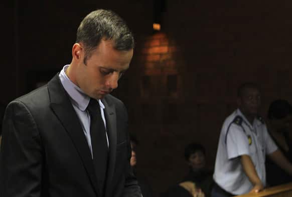 Olympic athlete Oscar Pistorius stands inside the court as a police officer looks on during his bail hearing at the magistrate court in Pretoria, South Africa.