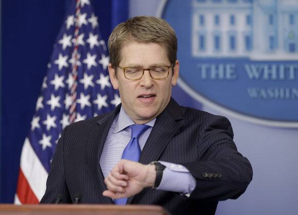 White House press secretary Jay Carney checks his watch before he briefs reporters at the White House in Washington.