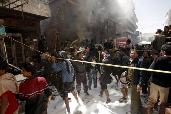 Yemeni people and soldiers try to extinguish fire at the site of a plane crash in Sanaa, Yemen.