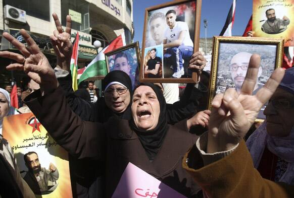 Women chant slogans, give the victory sign and display photographs of detained persons during a rally calling for the release of Palestinian prisoners jailed in Israel, in the West Bank city of Nablus.