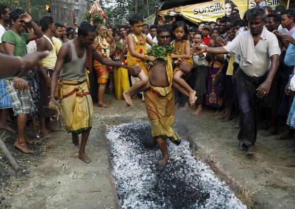 A Hindu man carries two girls while walking on burning embers during a traditional Hindu fire festival in Dalla, about 15 kilometers (9 miles) south of Yangon, Myanmar.