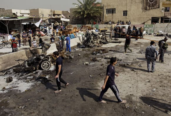 Iraqis inspect the scene of a car bomb attack in the Ameen neighborhood in eastern Baghdad, Iraq.