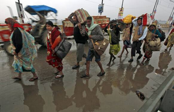 Hindu devotees walk on a bridge as it rains at Sangam, the confluence of the Rivers Ganges, Yamuna and mythical Saraswati, during Maha Kumbh festival, in Allahabad.