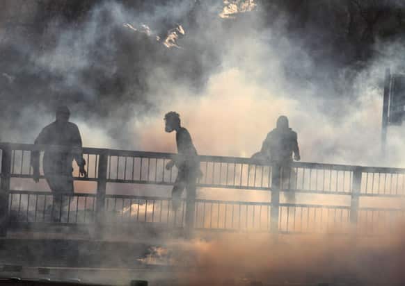 Bahraini anti-government protesters stand in clouds of tear gas fired by riot police during clashes in Daih, Bahrain.