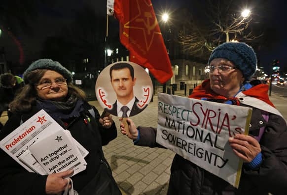 Anti-war protesters hold placards and a picture of Syria`s President Bashar Assad with the words