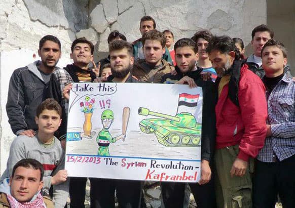 This citizen journalism image provided by Edlib News Network, ENN, which has been authenticated based on its contents and other AP reporting, shows anti-Syrian regime protesters holding a caricature placard during a demonstration, at Kafr Nabil town, in Idlib province, northern Syria.