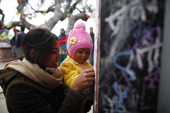 A Nepalese woman helps her child to write with chalk during an annual ritual to gain better education, on the walls of a Hindu temple meant for Goddess Saraswati to mark Saraswati puja festival, in Katmandu.