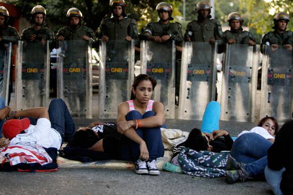 Students sit on the street outside Cuba`s embassy to demand information about the health of Venezuela`s President Hugo Chavez in Caracas, Venezuela.