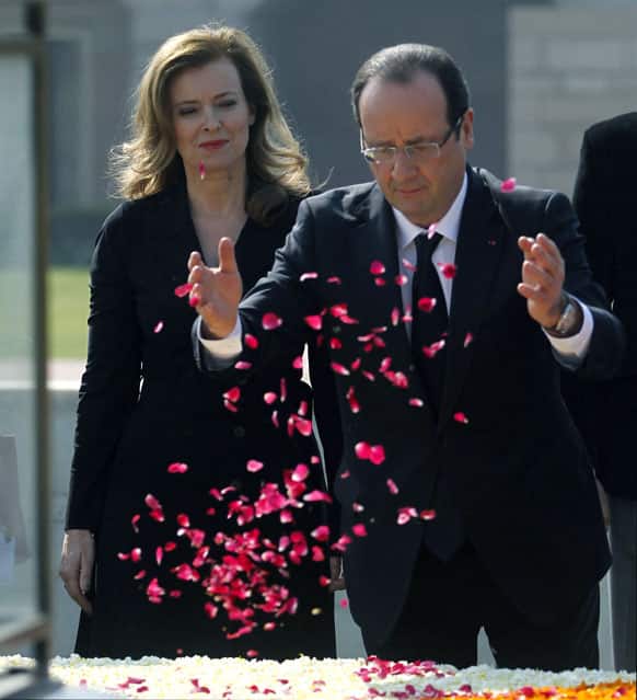 French President Francois Hollande, right, pays floral tributes as partner Valerie Trierweiler watches during a visit to the Mahatma Gandhi memorial in New Delhi.